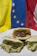 A close-up of a golden, crispy arepa filled with melted cheese and shredded beef, steam rising gently.