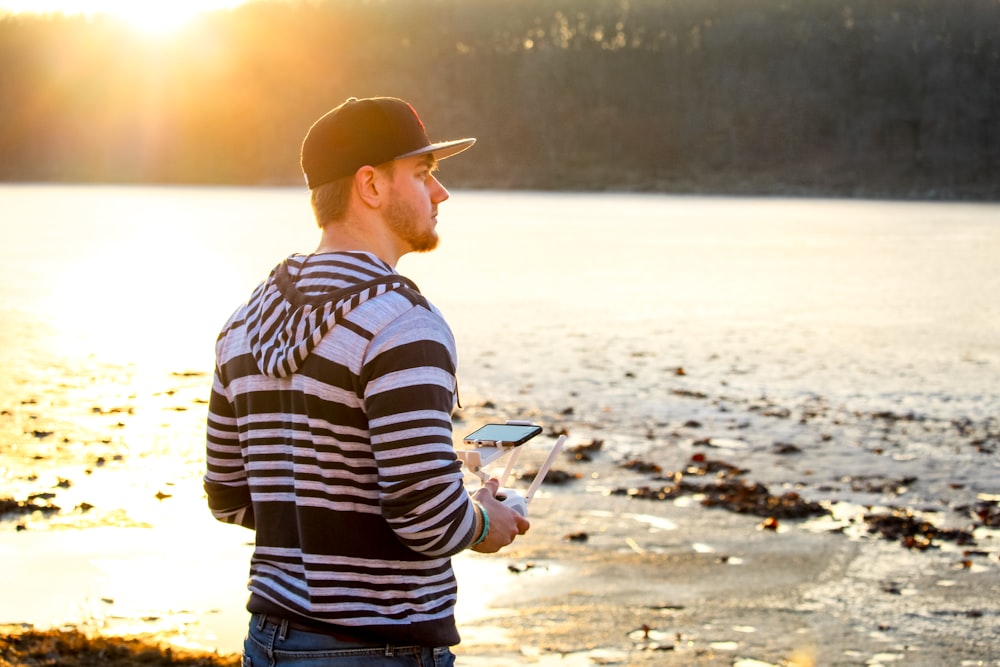 man in black and white striped long sleeve shirt standing on beach during sunset