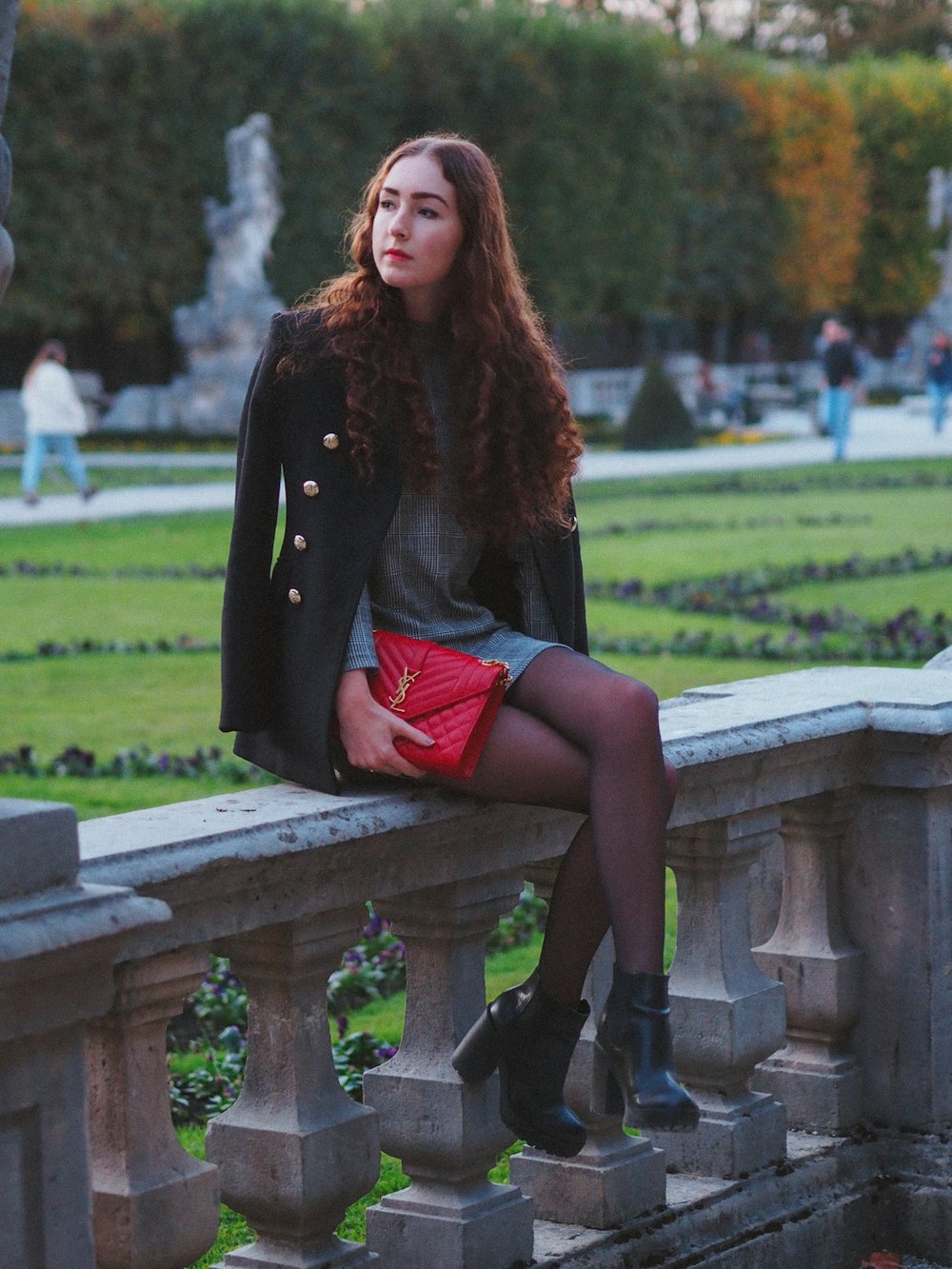 woman in black long sleeve dress sitting on brown wooden bench during daytime