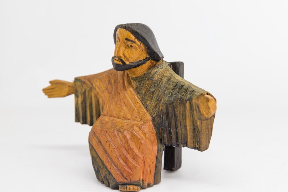 homme en bois brun tenant une figurine de livre