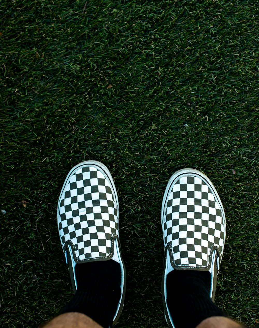 persona que usa zapatos sin cordones a cuadros blancos y negros