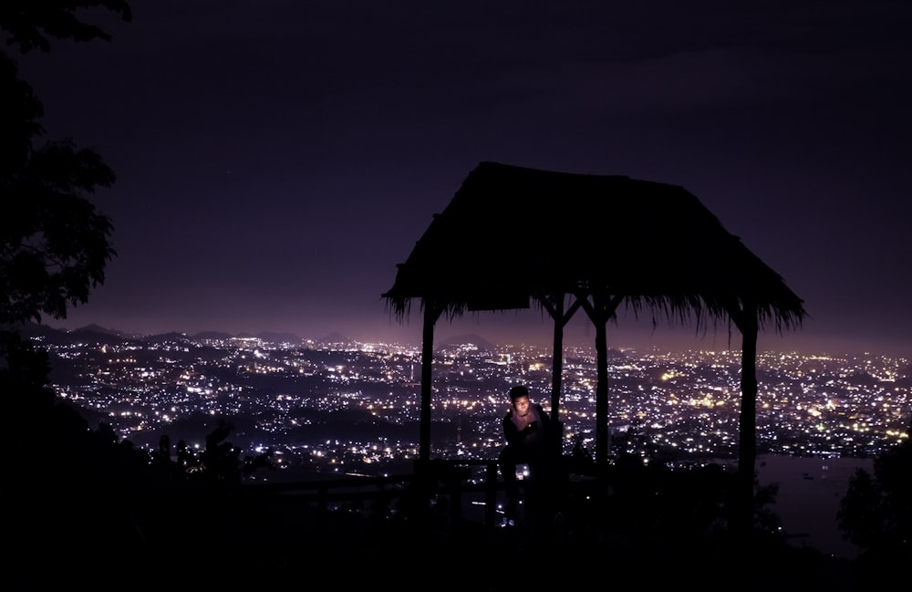 silhouette of 2 people sitting on beach shore during night time