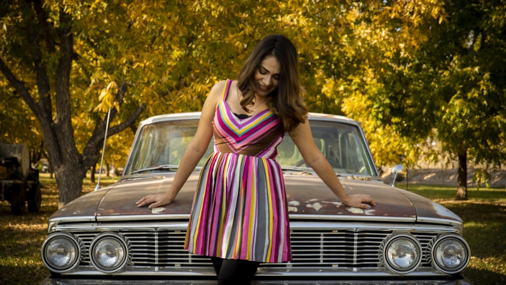 woman in pink and white stripe dress standing beside black car during daytime