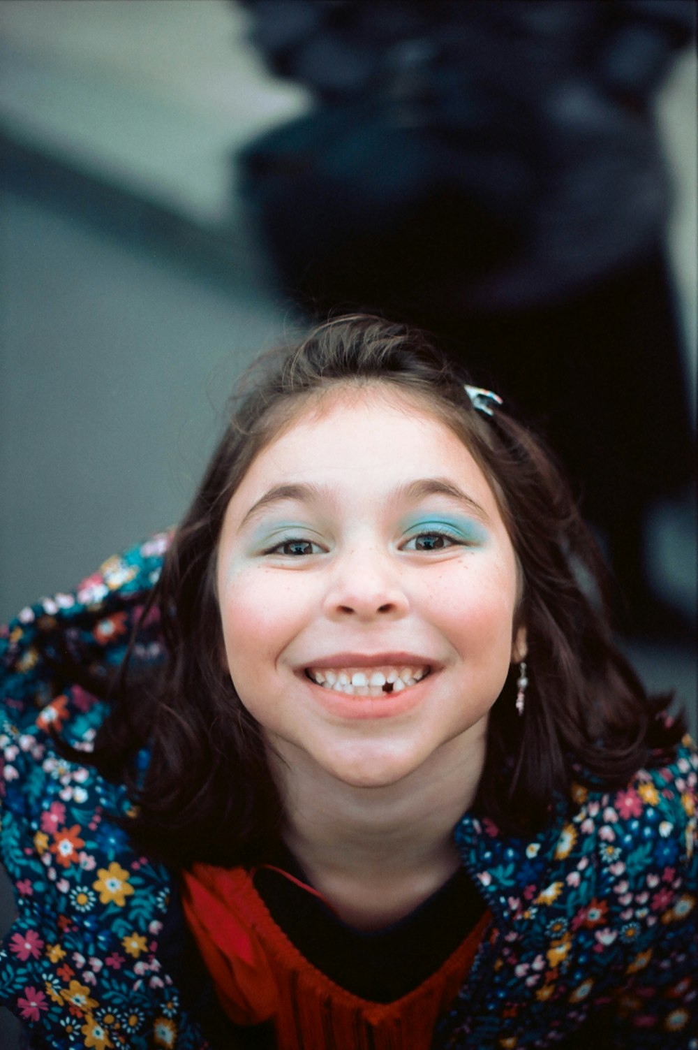 menina sorridente na camisa floral azul e vermelha