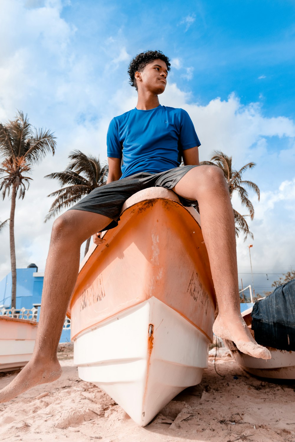 man in blue crew neck t-shirt sitting on orange and white boat during daytime