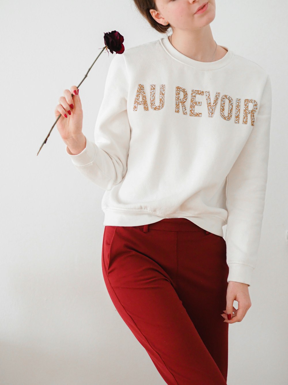 a woman in a white sweater holding a flower