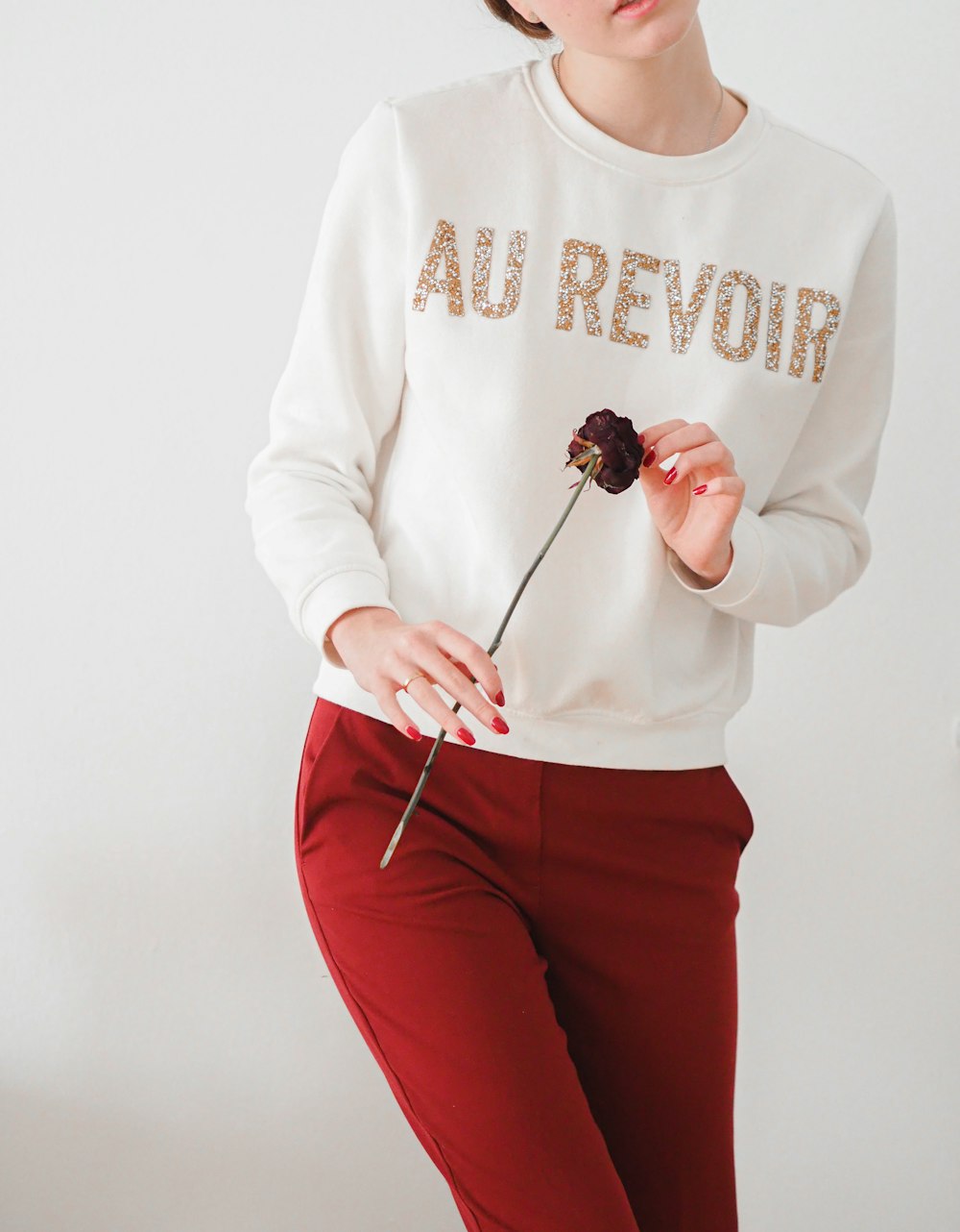 woman in white long sleeve shirt and red pants holding silver spoon