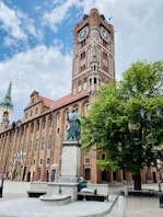 brown concrete building with statue of man and woman walking on sidewalk during daytime