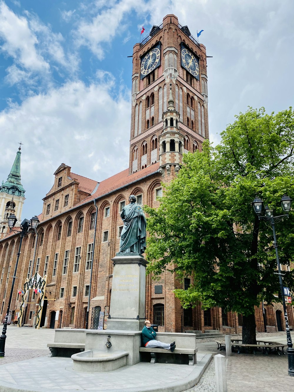 brown concrete building with statue of man and woman walking on sidewalk during daytime