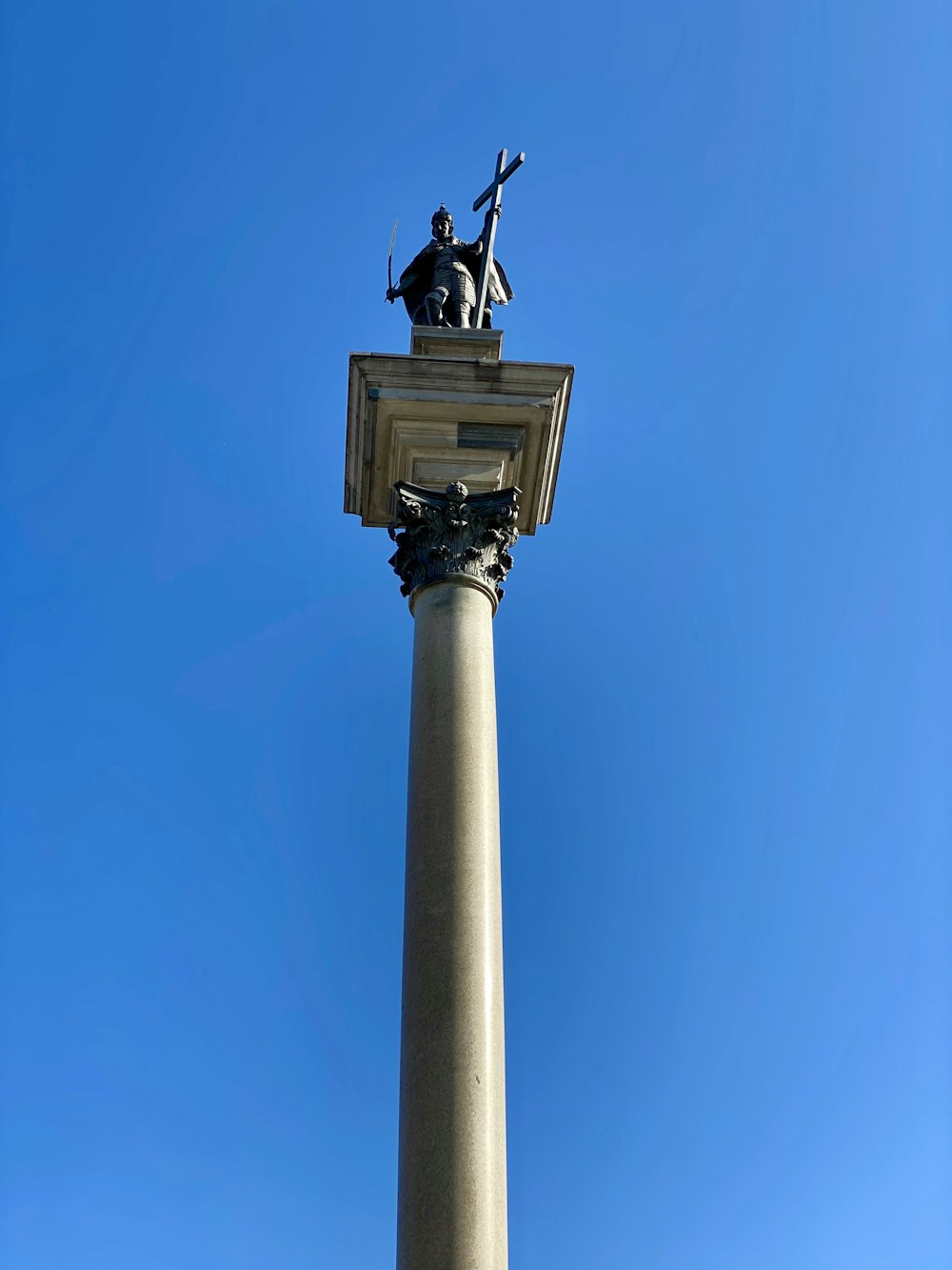 black bird on white concrete post under blue sky during daytime