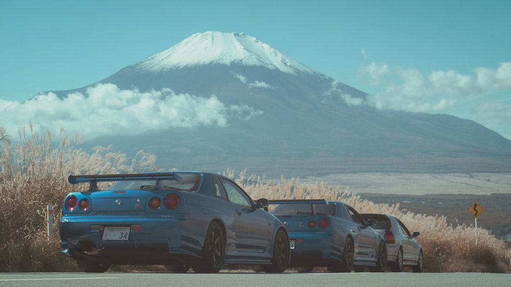 日中の雪山近くの道路を走る青いBMWクーペ