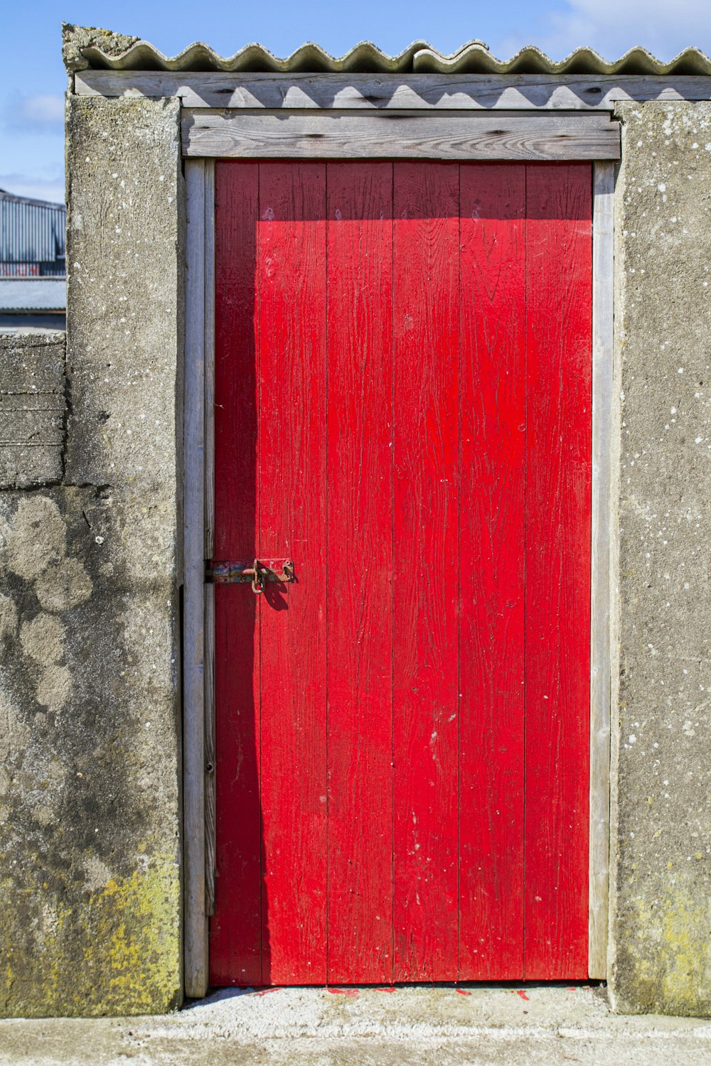 灰色のコンクリートの壁に赤い木製のドア