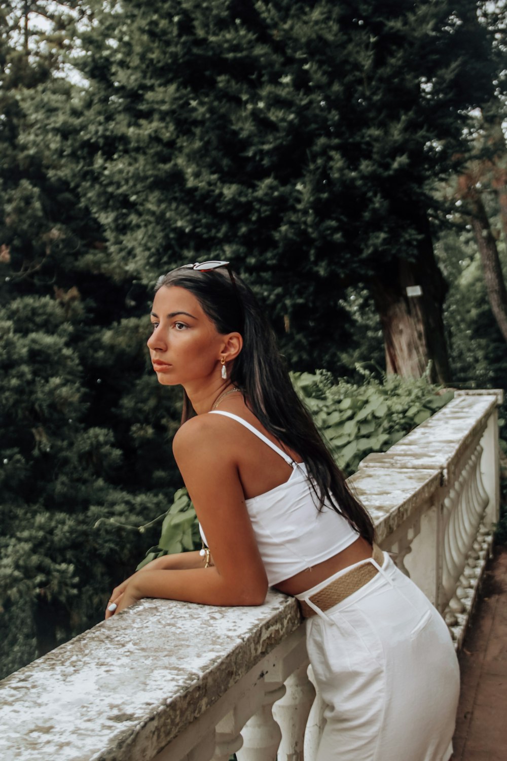 woman in white spaghetti strap top sitting on concrete bench