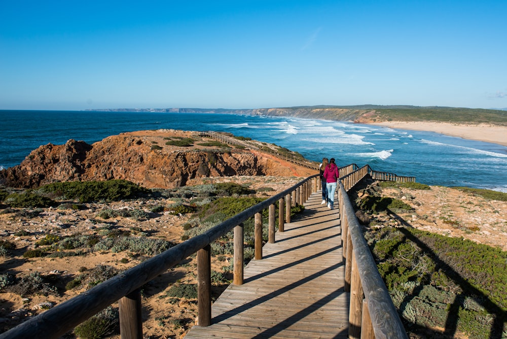 woman in red jacket walking on wooden bridge