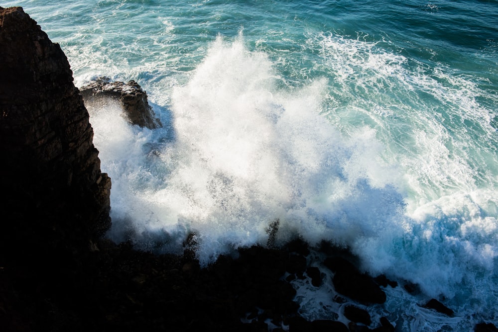 ocean waves crashing on rocky shore during daytime