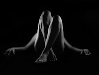 A person lying on their back with knees raised against a black background