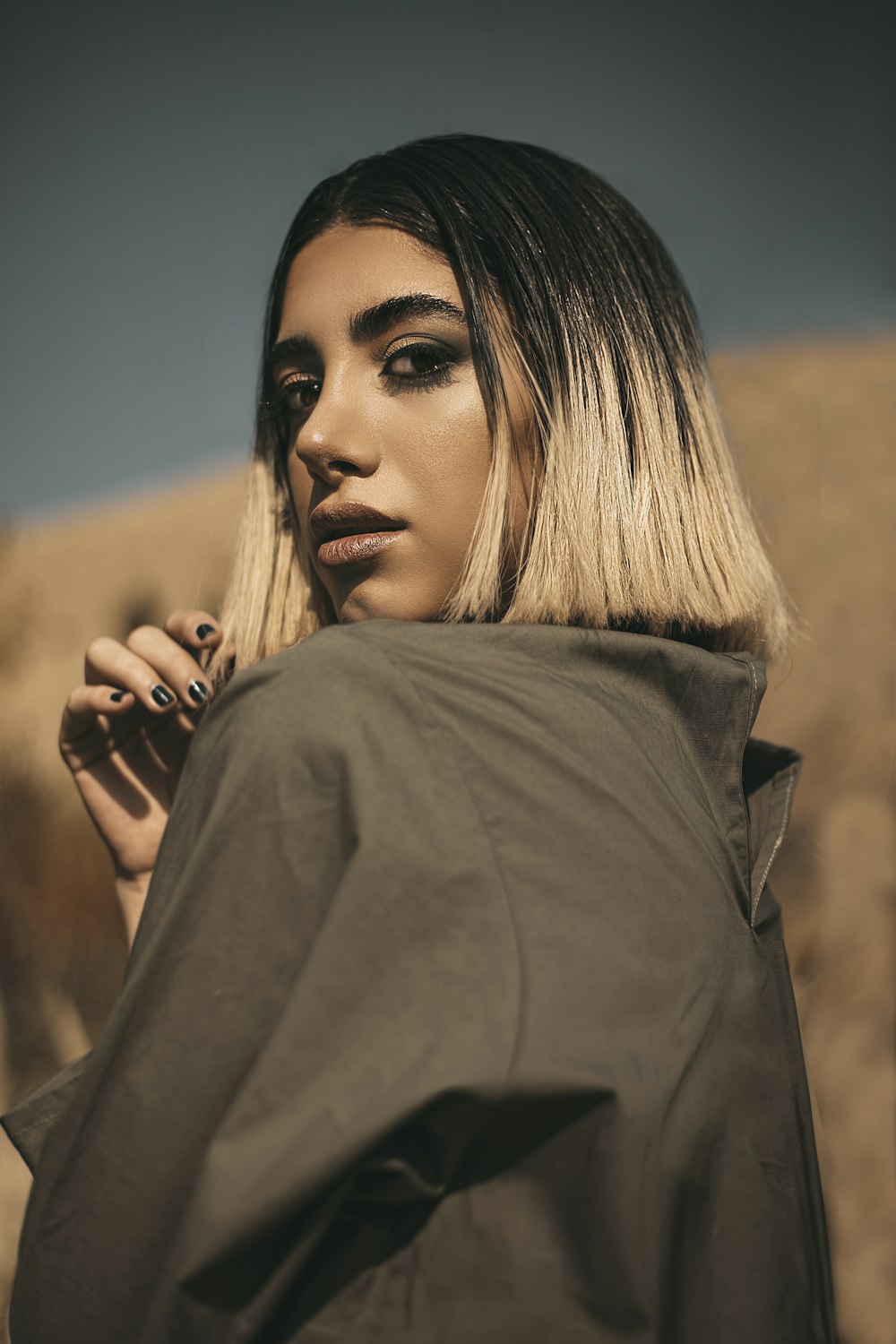 woman in gray coat holding her hair