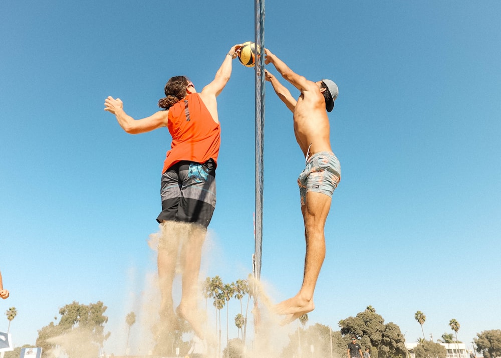 man in orange t-shirt and blue denim shorts holding silver pole during daytime