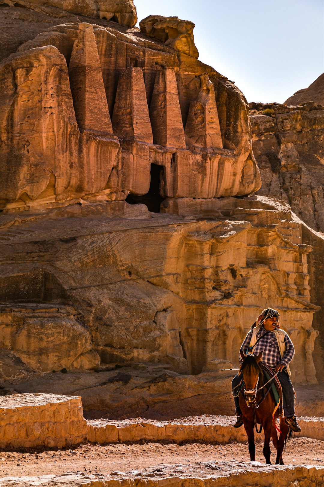 woman in black and white checkered dress shirt standing on brown rock formation during daytime