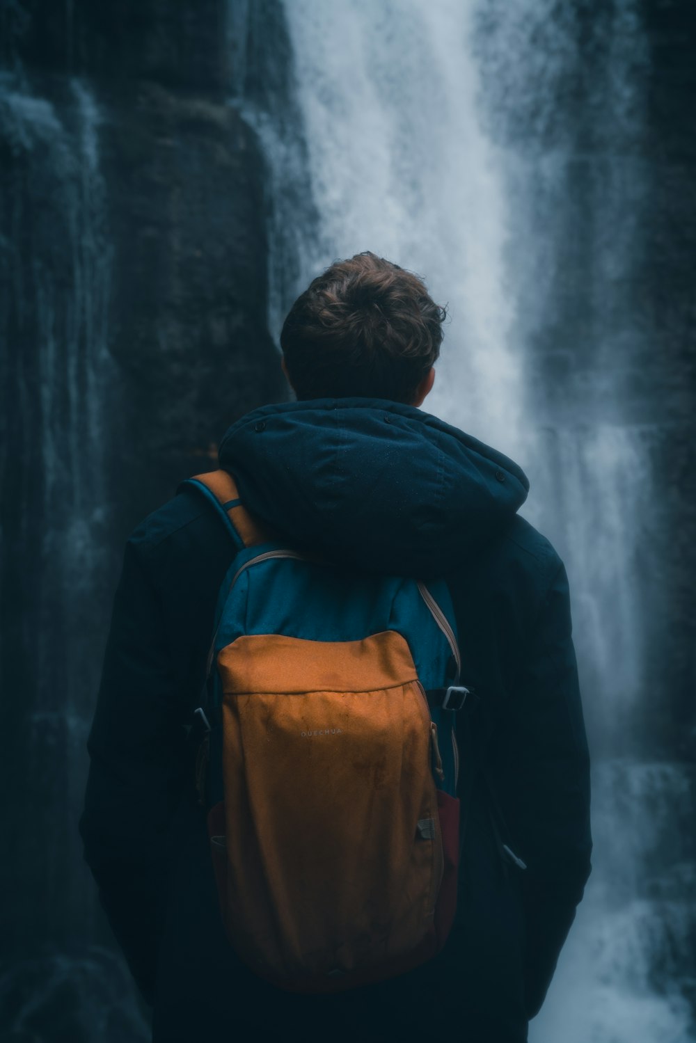 Hombre con sudadera con capucha azul y mochila naranja