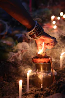 Close-up of hands lighting a candle in a spiritual ritual setting with elements symbolizing Mãe Oxum.