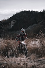 man in red and black motorcycle suit riding on red and white motocross dirt bike