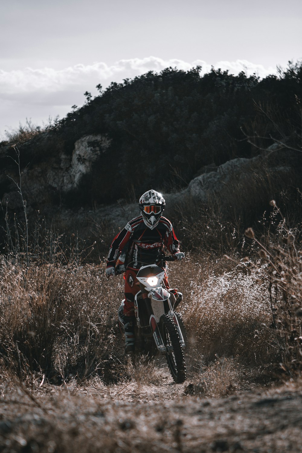 Hombre en traje de motocicleta rojo y negro montando en moto de cross de motocross roja y blanca