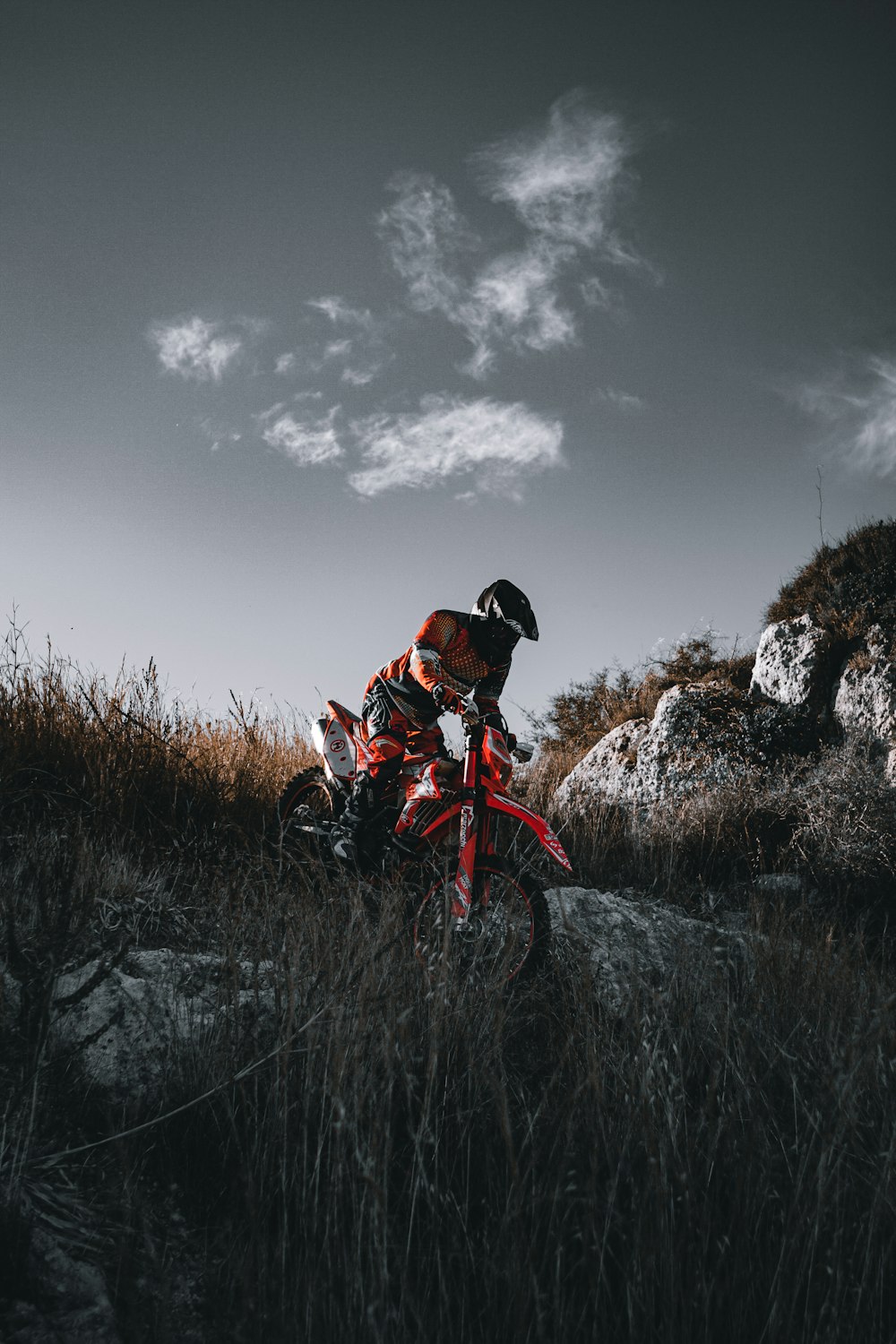 man in orange jacket riding on red dirt bike