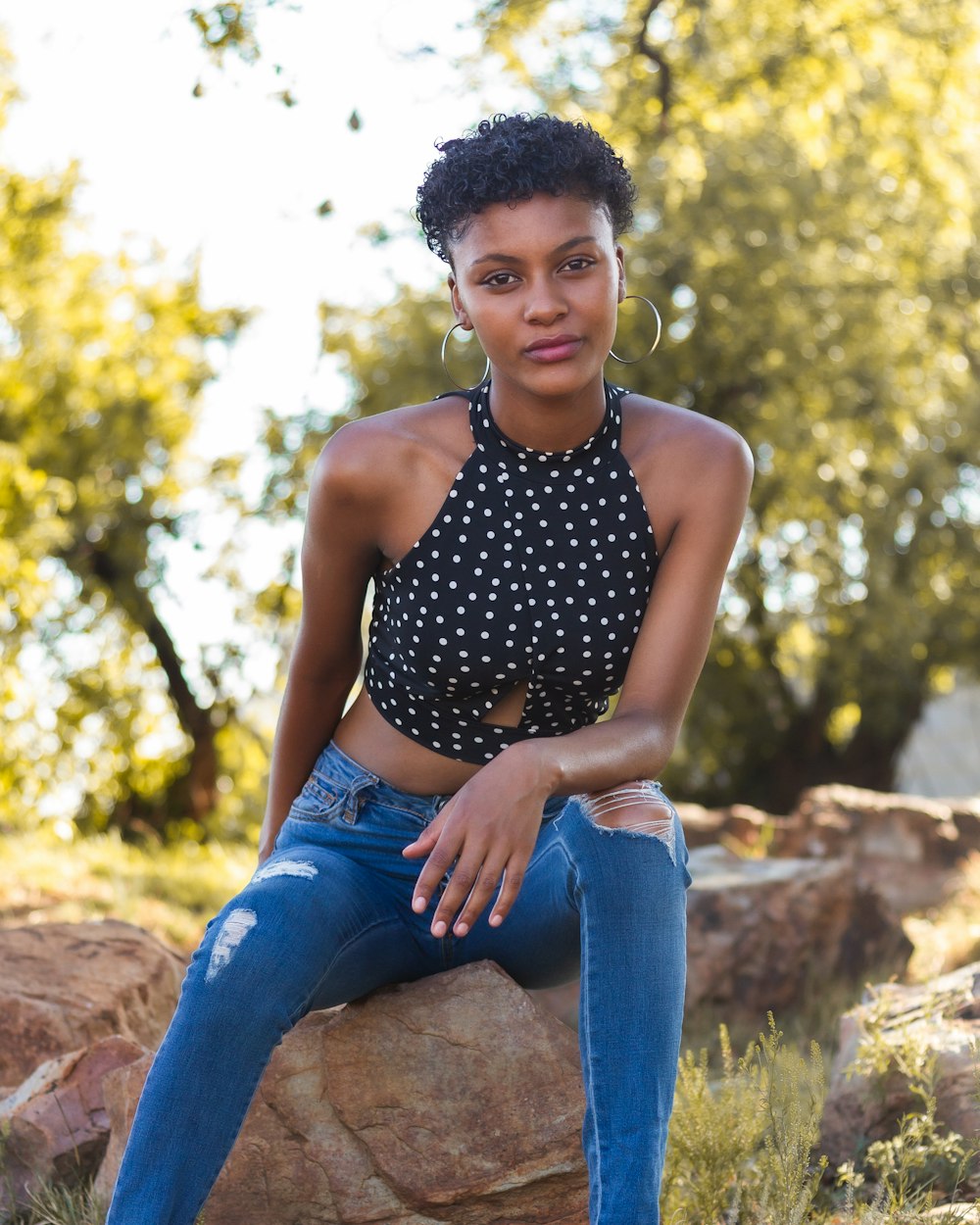 woman in black and white polka dot tank top and blue denim jeans sitting on brown