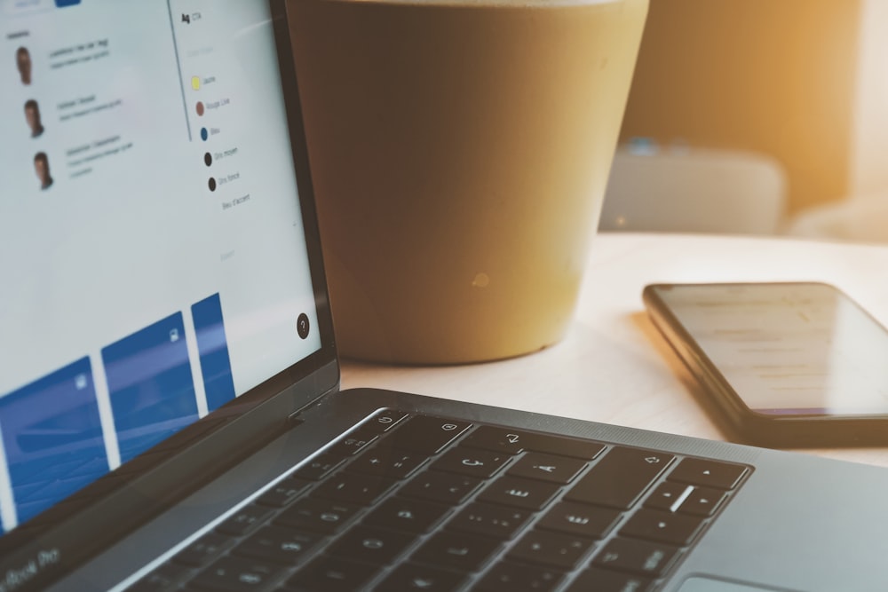 white laptop computer turned on beside brown paper cup