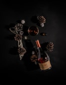 A glass of amber Cognac resting on a wooden table beside a vintage corkscrew.