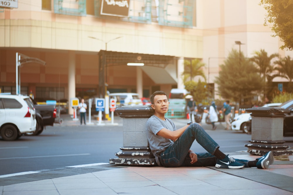 man in blue denim jeans sitting on black skateboard on road during daytime