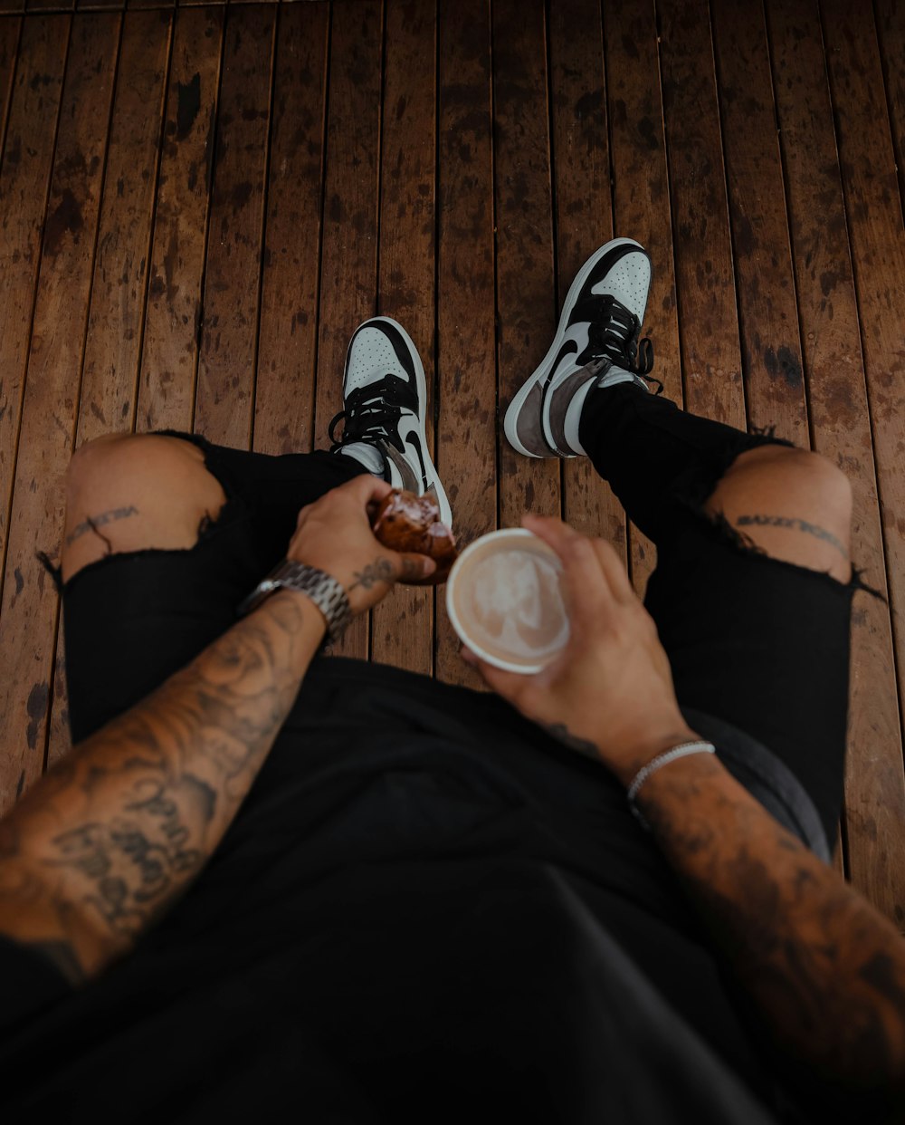 person in black pants and black and white nike sneakers holding clear drinking glass