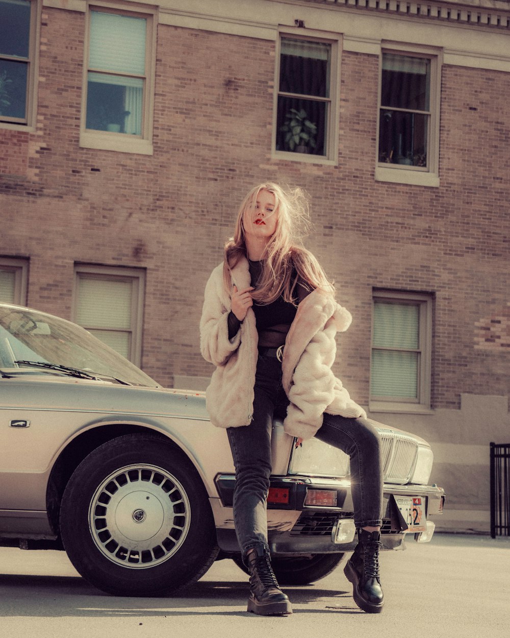 woman in beige coat standing beside white car