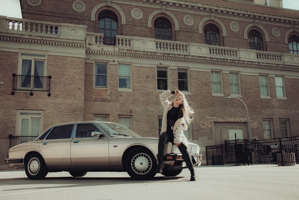 woman in white long sleeve shirt and black pants standing beside silver sedan during daytime