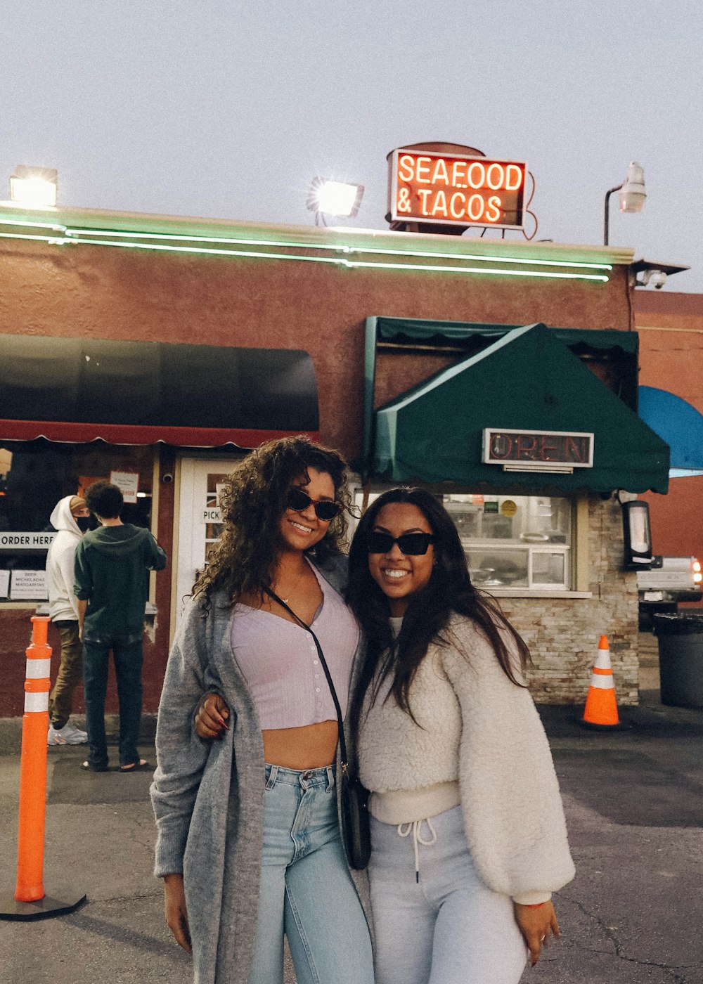 woman in white cardigan standing beside woman in gray cardigan