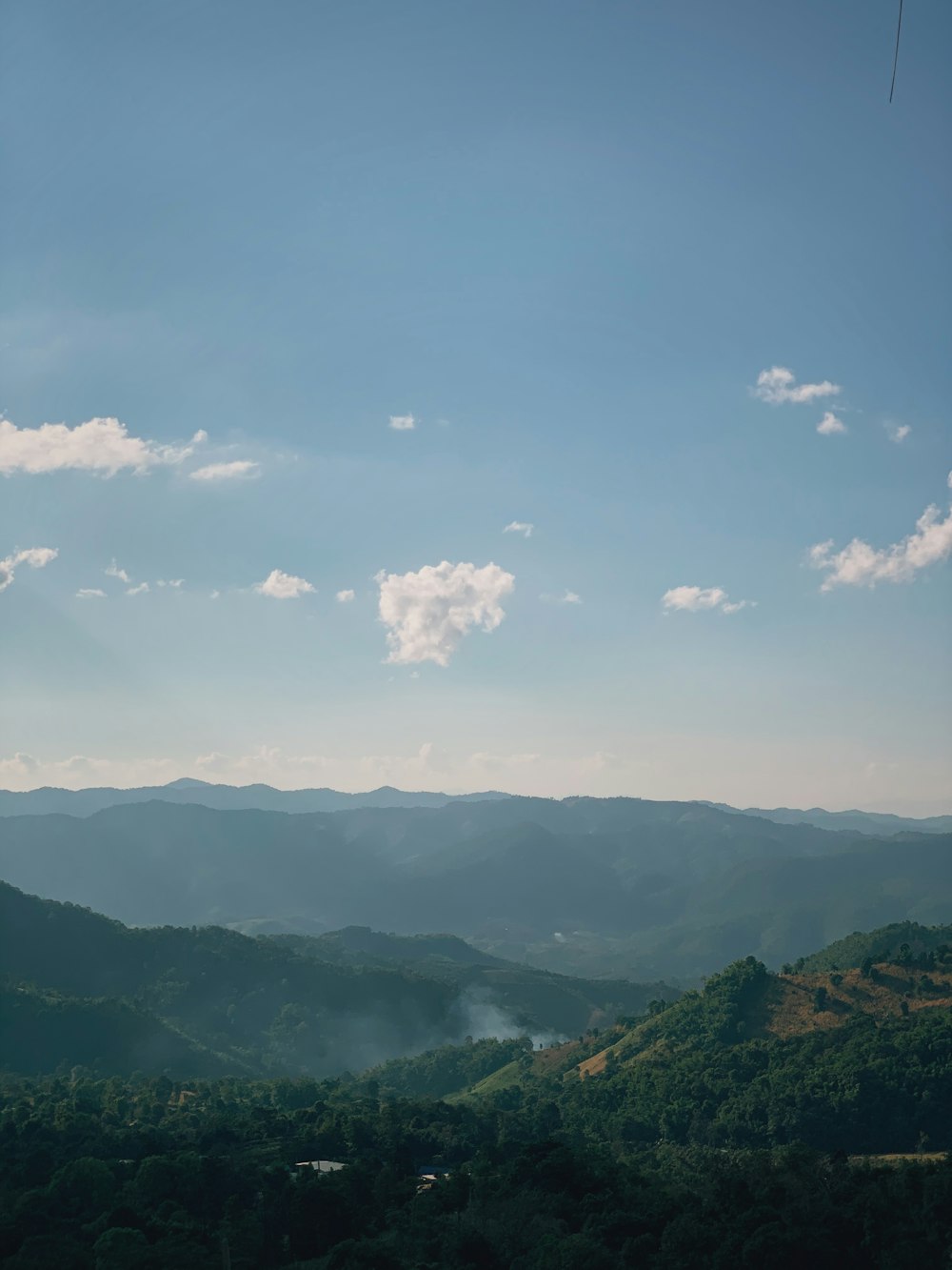 昼間の白い雲の下の緑の山々