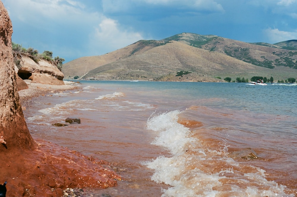 brown and green mountain beside body of water during daytime