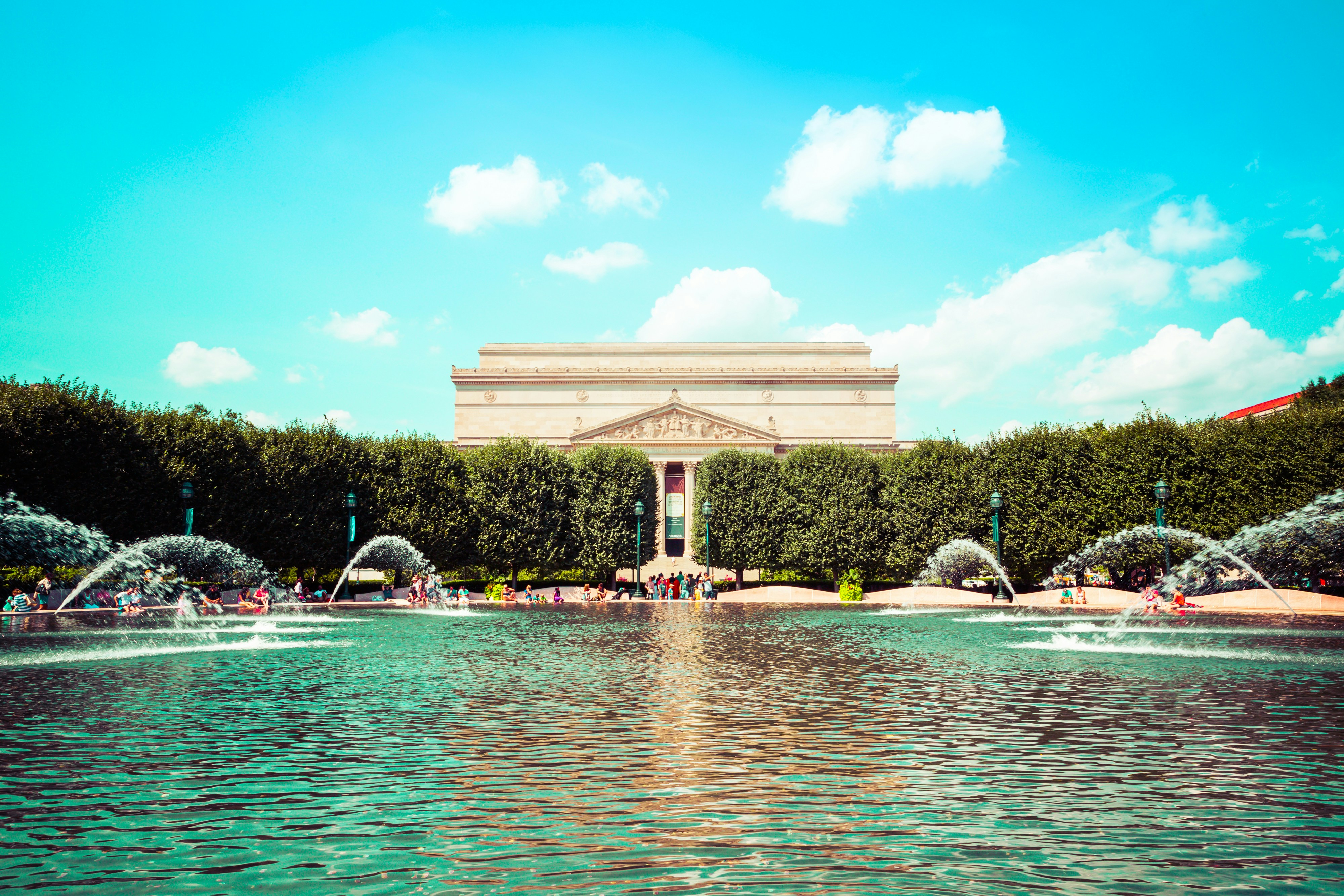 people in water fountain near beige concrete building during daytime