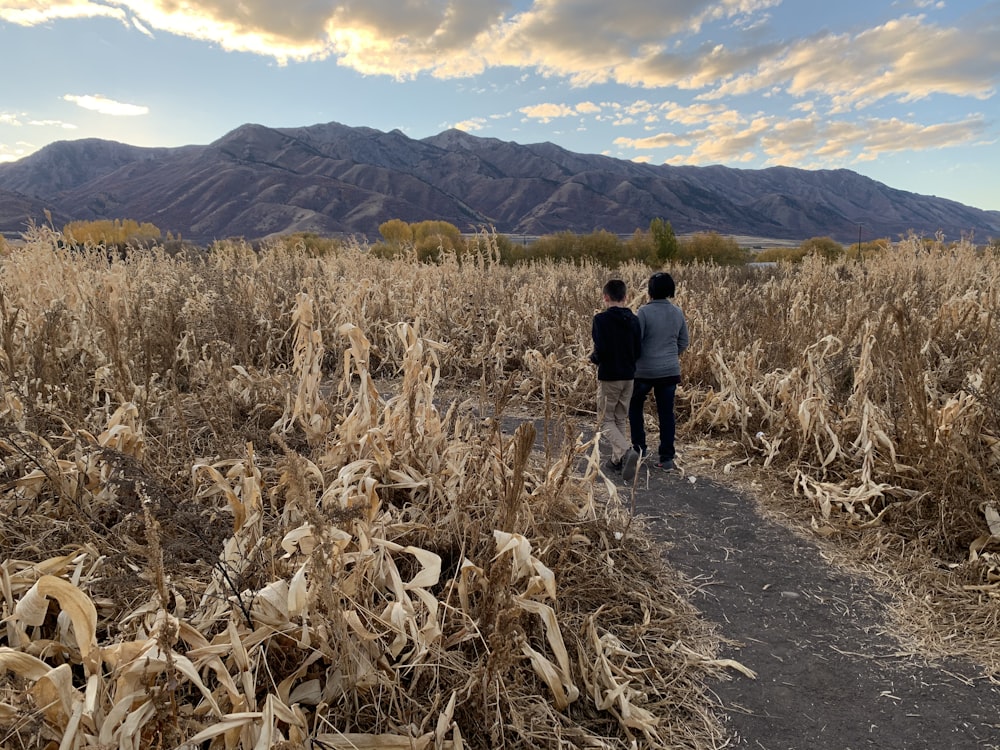 man in black jacket walking on brown field during daytime