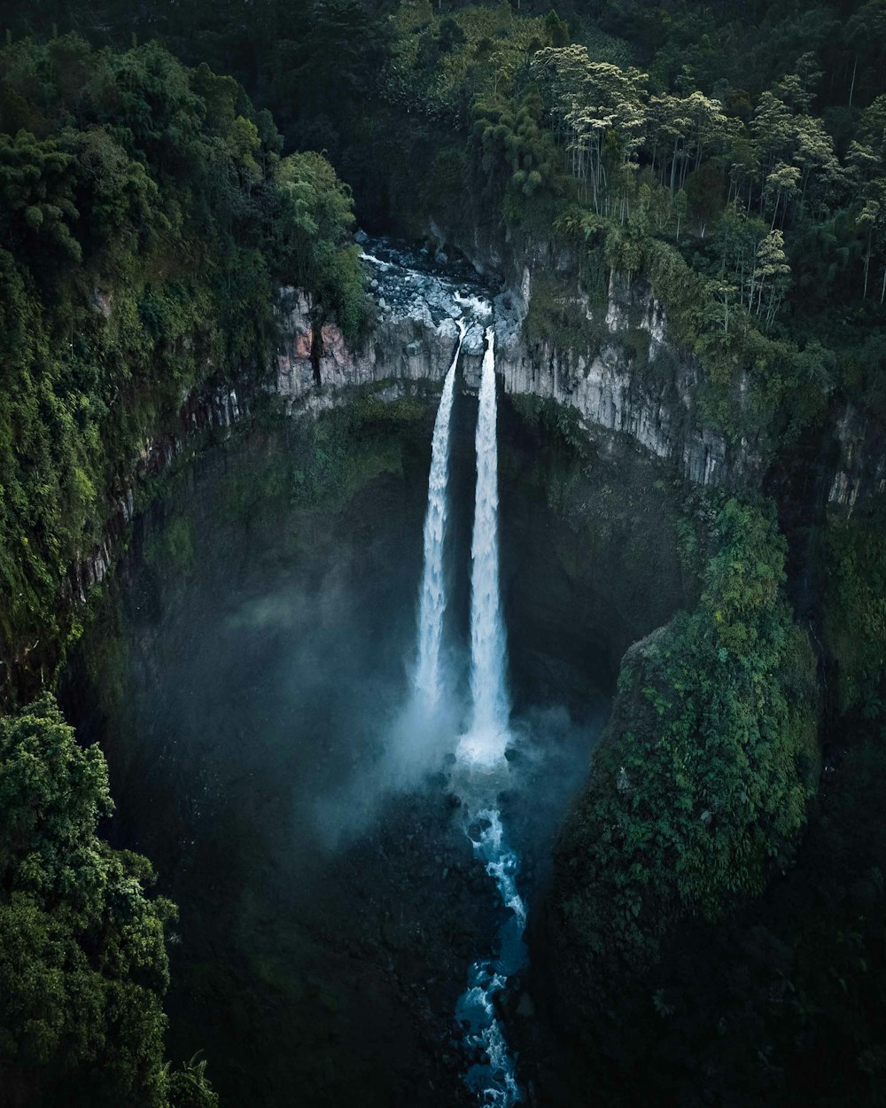 waterfalls in the middle of green trees