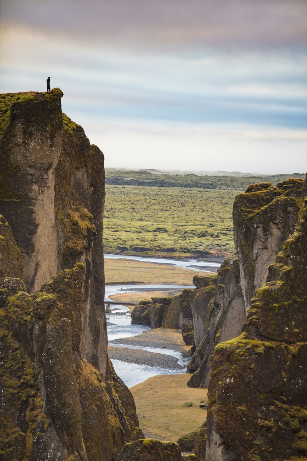 person standing on rock formation near body of water during daytime