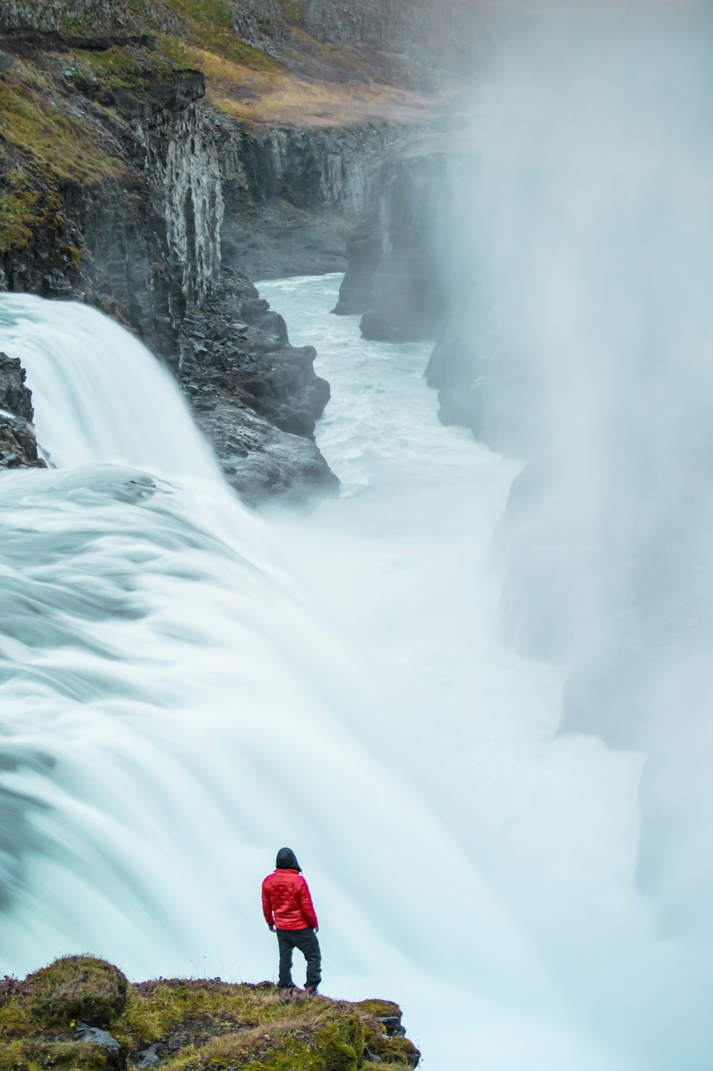 person in red jacket and black pants sitting on white snow covered ground