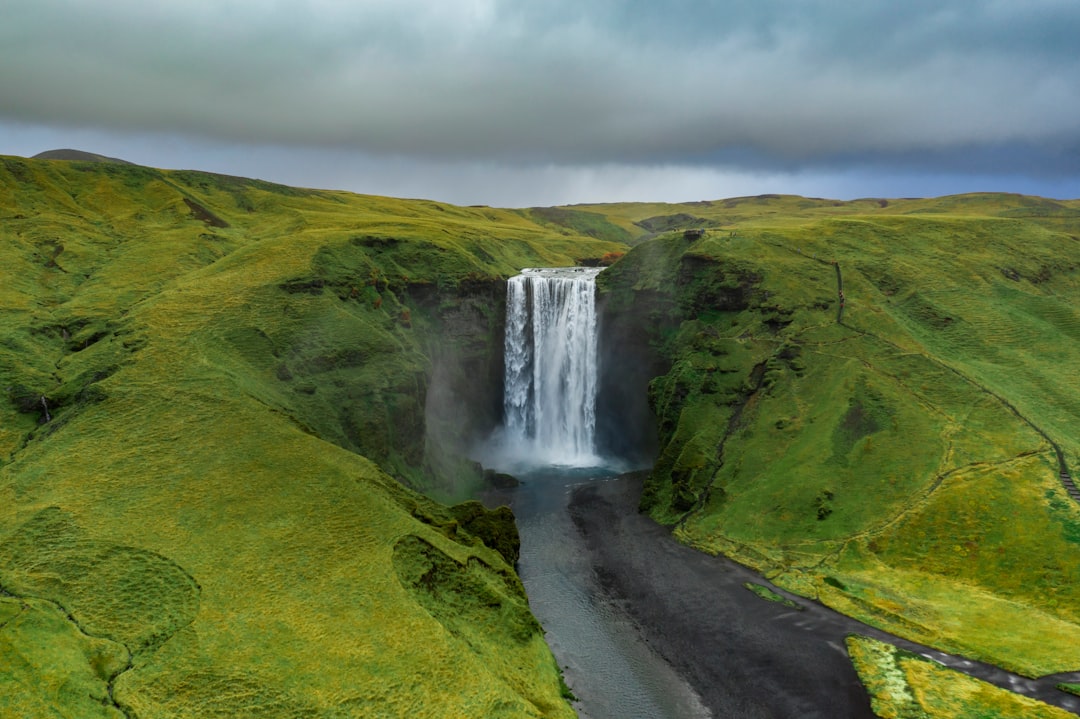 waterfalls on green grass field under white clouds during daytime