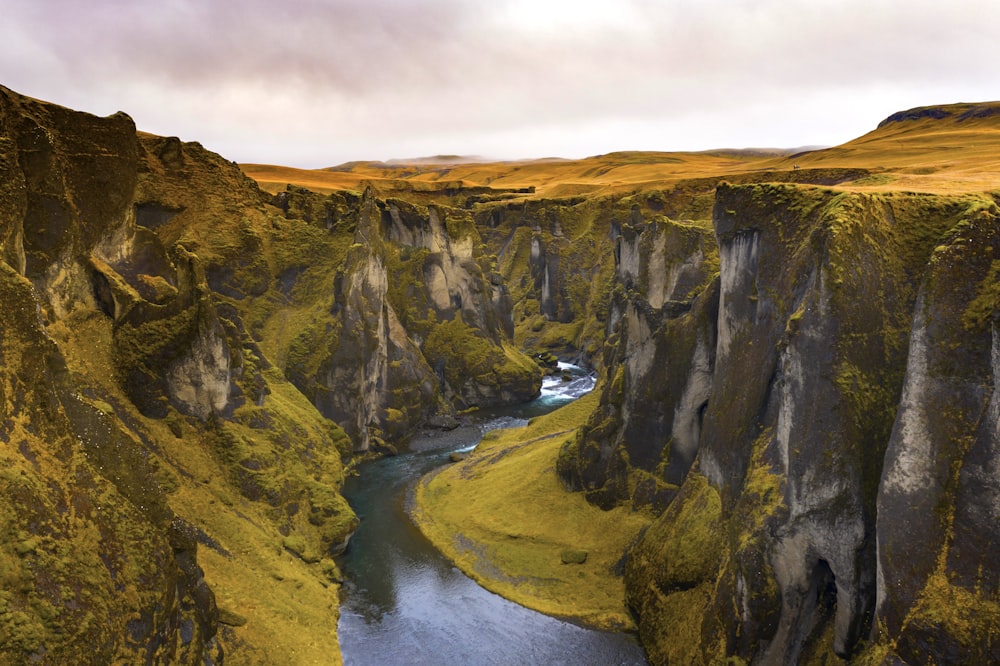 brown and green mountain beside river during daytime