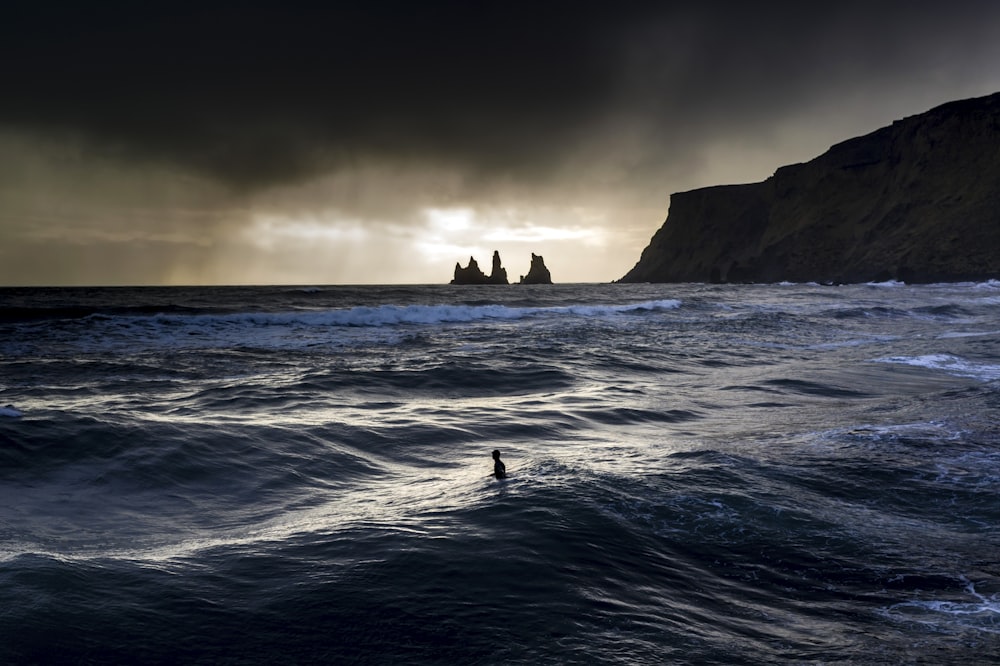 silhouette of rock formation on sea during daytime