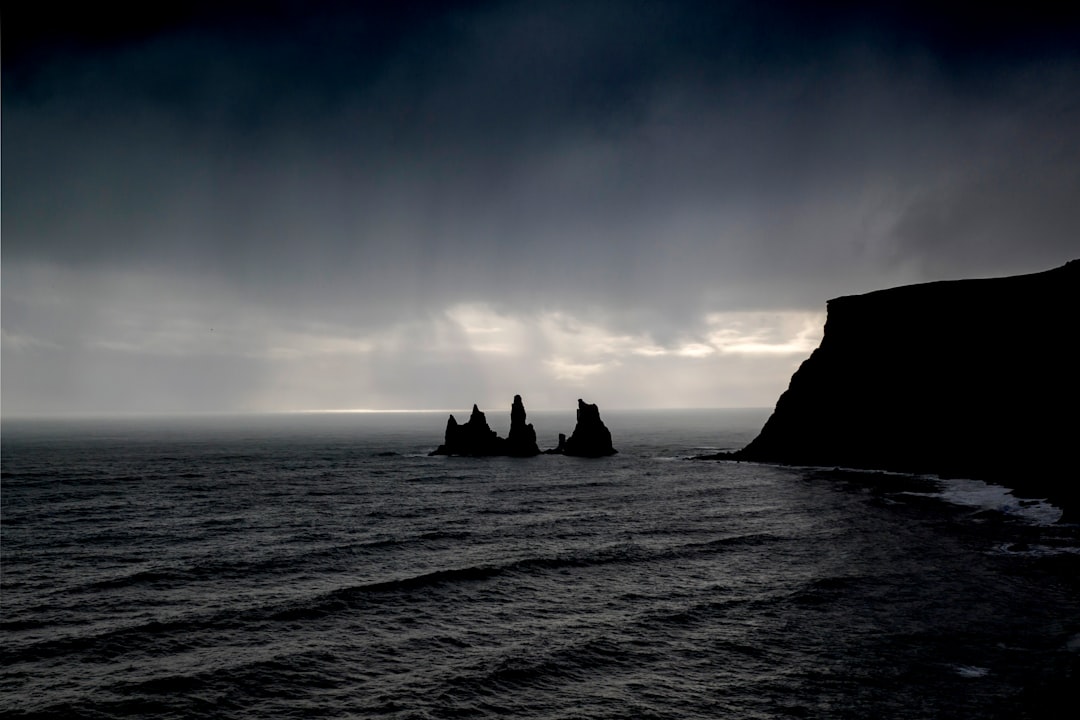 silhouette of rock formation on sea during daytime