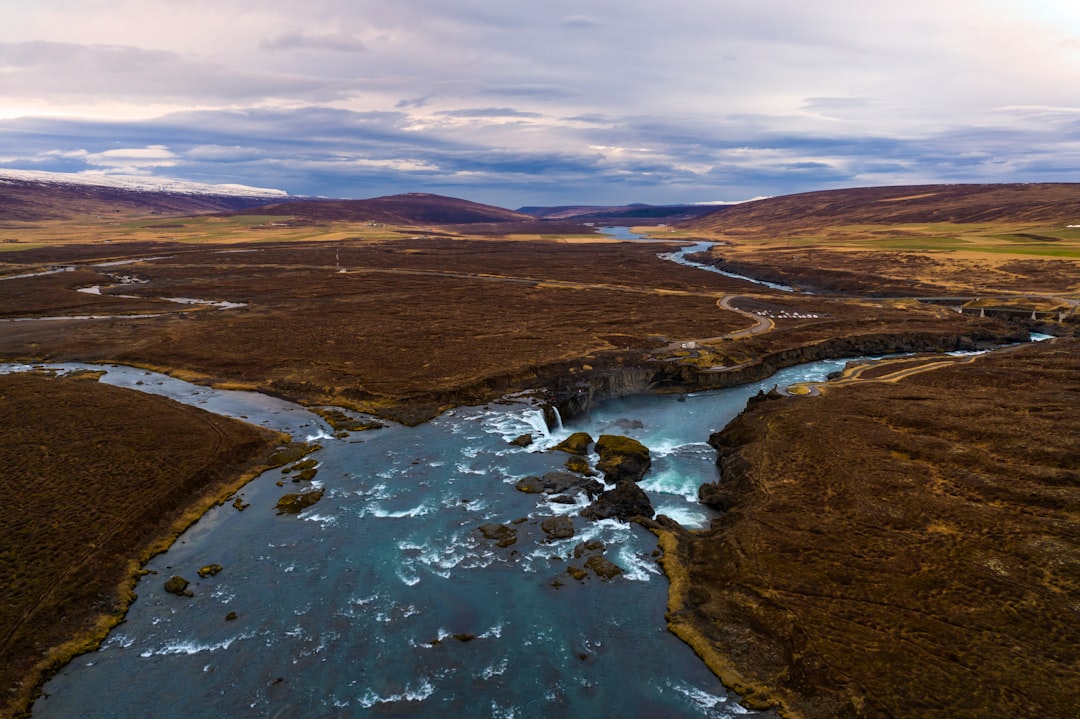 river in the middle of brown field