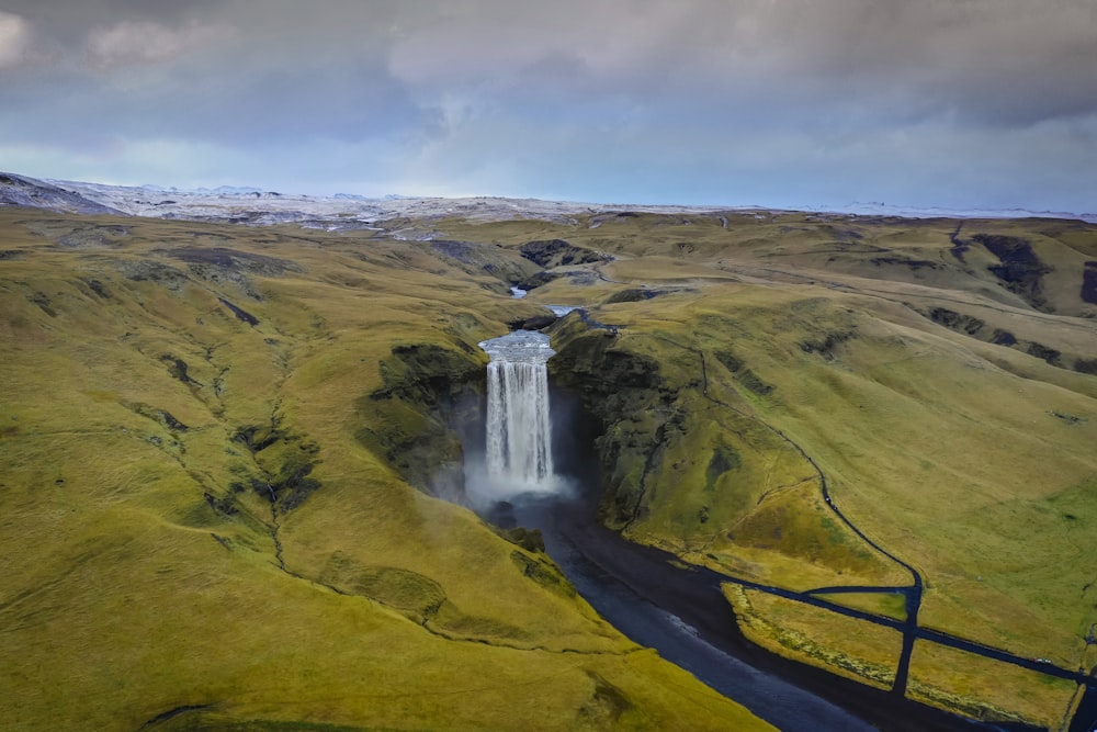 cascadas en un campo de hierba verde bajo nubes blancas durante el día