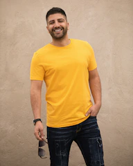 man in yellow crew neck t-shirt and black denim jeans standing beside white wall